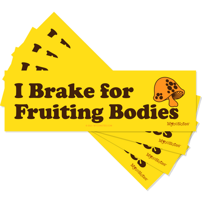 Stack of yellow bumper stickers with 'I Brake for Fruiting Bodies' text and mushroom illustration